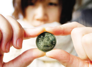 昨日，一位市民在展示购买到的马年纪念币背面。新华社发