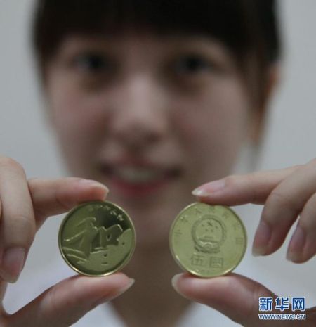 9月23日，在上海金山区象州路上的一家农业银行，一名工作人员正在展示“和”字书法——行书普通纪念币。