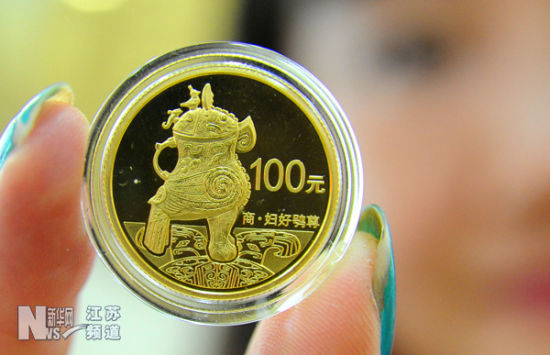 一名苏州姑苏金店工作人员在展示1/4盎司的中国青铜器金质纪念币