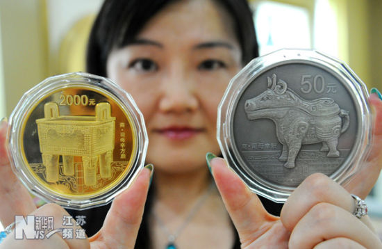 苏州市姑苏金店工作人员展示新上市的两枚中国青铜器金银纪念币