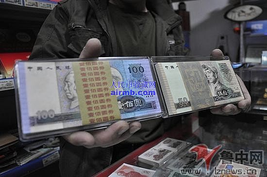 这位店主柜台里99版的已经销售一空，手里拿着的是90版的人民币。全媒体记者刘冰摄