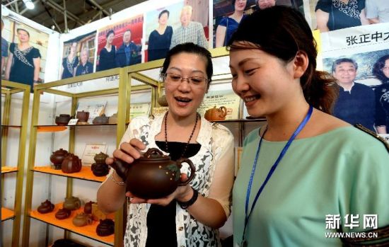 8月7日，来自江苏宜兴的工艺美术师李利（左）在紫砂艺术节上展示自己的作品。