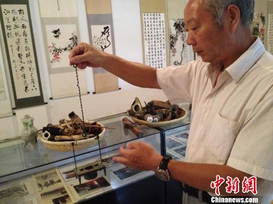 王开华老人在展示自己所收藏的民俗传统器物。刘林摄