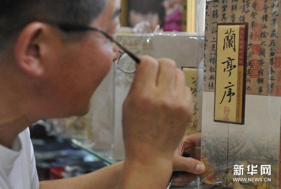 一名顾客在浙江省湖州市天韵绸庄内欣赏真丝织锦书法作品《兰亭序》。
