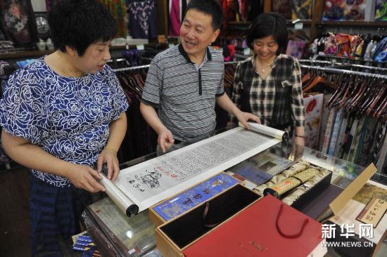 湖州市天韵绸庄“庄主”汤剑峰（中）在为顾客介绍真丝织锦书画作品《道德经》。