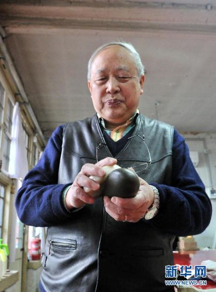 年过六旬的古书画修复专家徐建华手拿的是一直陪伴着他的砑石和川蜡，这是古书画修复的工具（1月25日摄）。