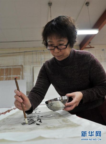 故宫博物院的文物保护技术人员常洁正在为一幅书法作品进行固色，就是把画面上容易掉色部分用胶进行加固（1月25日摄）。