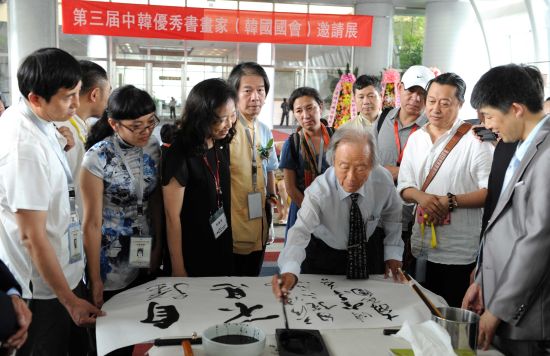 图四：展览开幕式现场，韩国国会议员书道会教授、国际书协韩国本部名誉顾问高岗先生现场挥毫，以“厚德载物”四字相赠。