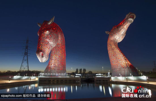 当地时间2014年10月28日，英国苏格兰福尔柯克，著名马头形雕塑“马头水鬼”全身挂满红灯，在夜幕下赫然屹立震撼无比。