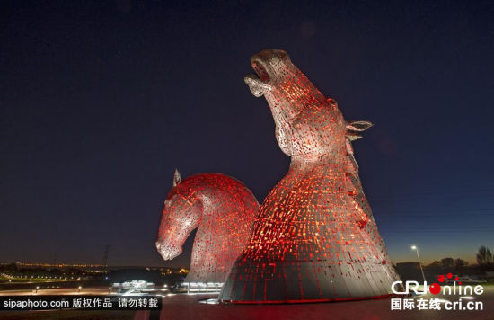 当地时间2014年10月28日，英国苏格兰福尔柯克，著名马头形雕塑“马头水鬼”全身挂满红灯，在夜幕下赫然屹立震撼无比。