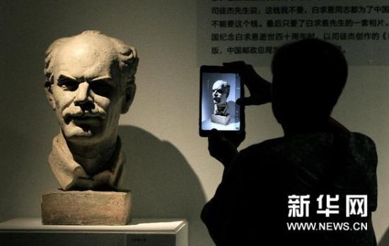 8月5日，一名参观者在展览上拍摄白求恩纪念像。新华网图片 高静 摄