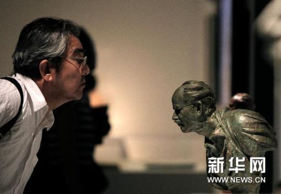  8月5日，一名参观者在展览上观看白求恩头像雕塑作品。新华网图片 高静 摄
