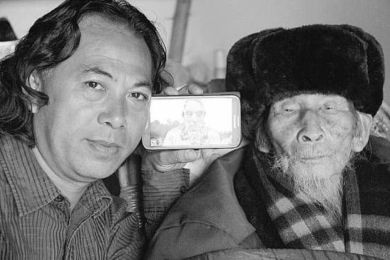 李春华用手机向老兵付心德展示他的雕塑