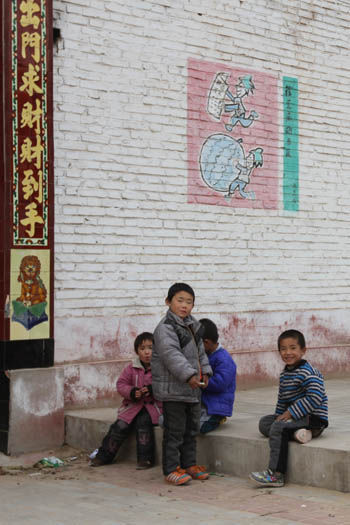 西临河村一群玩耍的孩子们身后的白墙上，是郝增茂画的一幅漫画。