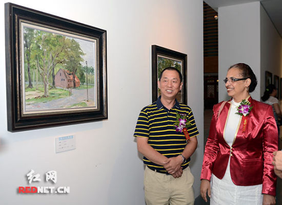(蔡国胜（左）陪同苏里南驻华使馆代办桑德拉女士参观在北京举行的“魅丽苏里南——蔡国胜、安滨油画、水彩写生展”。)