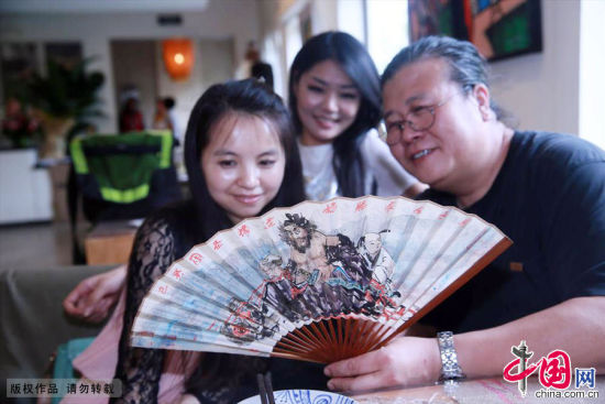 2013年07月10日，北京，著名京味画家杨信介绍自已创作的旧京民俗扇画。中国网图片库 陈晓根/摄