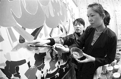 3月17日，在广西三江侗族自治县独峒乡，两名侗族妇女在研讨一幅大型壁画的色彩。