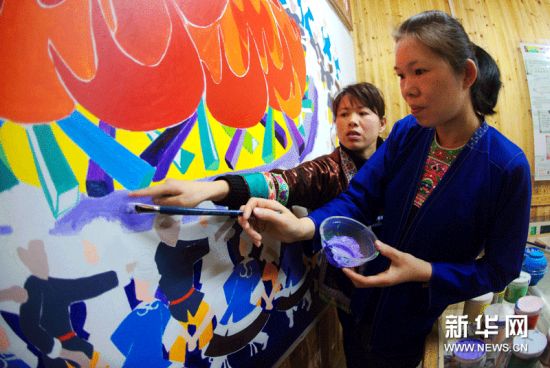 在广西三江侗族自治县独峒乡，两名侗族妇女在研讨一幅大型壁画的色彩。