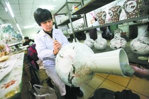 北京非遗技艺仿古瓷工艺大师白莉在工作室内为“九桃天球瓶”洗染上色。 本报记者 方非摄