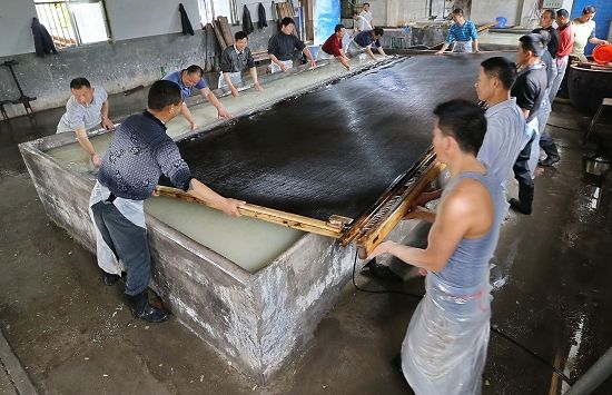 安徽省泾县纸工制作巨型纸“三丈特宣”捞纸的现场，此道工序需要十多位工人协调配合才可进行 谢震霖 图