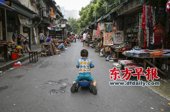 8月16日，东台路古玩市场里游客不多，一个小男孩滑着滑轮车在市场里玩耍。