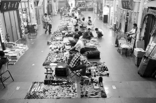 7月1日，在武汉崇仁路收藏市场内，藏友们在地摊上“淘宝”。本报记者 傅坚 摄