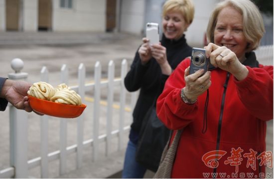 4月24日，西安 两位美国专家对工作人员吃的花卷很感兴趣； 本报记者陈团结摄影
