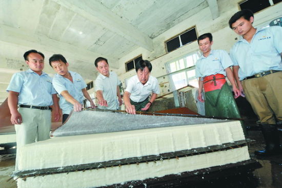 邢春荣（右三）向工人传授捞纸技艺。