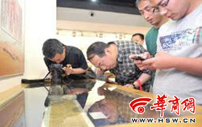 5月26日，陕西省图书馆，“丝绸之路西北地区珍贵古籍大展”上，38岁的张先生（左）隔着玻璃翻拍古籍 本报记者 袁琛 摄