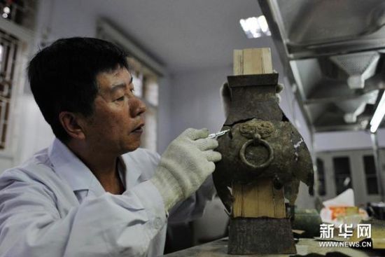 （1）7月15日，在天水市博物馆文物保护修复中心，文物保护专家李小龙在检查一件汉代青铜器文物的受损情况。