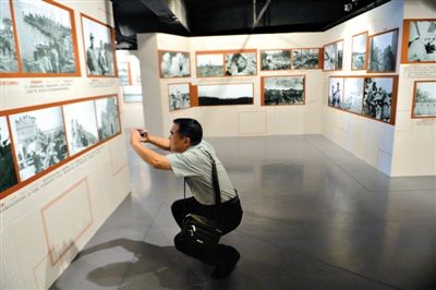 昨日，抗战纪念馆,一位观众观看展览照片，并用手机翻拍下来。新京报记者 吴江 摄