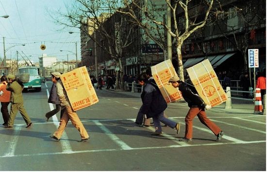 人们背着上海水仙牌洗衣机过马路的照片，定格了改革开放初期真实的生活水平。唐载清 图