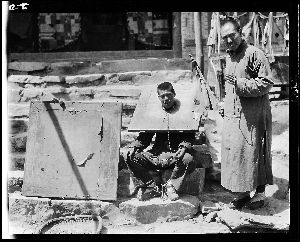《戴枷的男子》 　　照片拍摄的是一个戴着枷锁的男人坐在一位僧人身边。很多人以为这个男人是名囚犯，但专家发现，他戴枷锁其实是为了还愿。