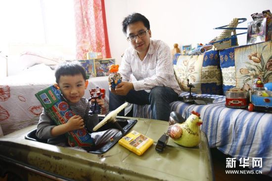 朱宇翔和儿子坐在堆满老玩具的房间里。