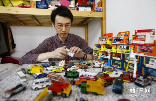王帆在家中摆弄他收藏的小车模型。