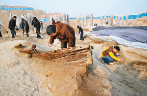昨日，在渭河桥遗址的厨城门一号桥北端，考古工作人员正在清理发掘出的古船