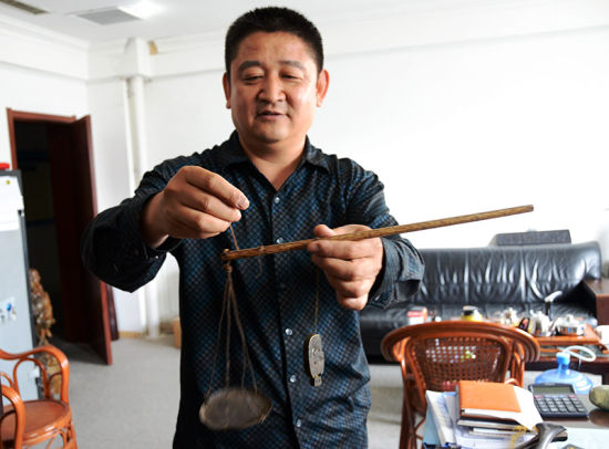 秤砣收藏家张奎生正在展示罕见的子母秤。（摄影：陈心同）