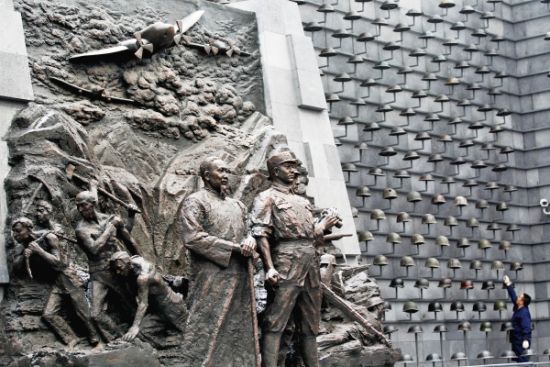 滇西抗战纪念馆大堂三面墙上呈矩阵式排列的钢盔。正中的雕塑代表了抗战的主要力量