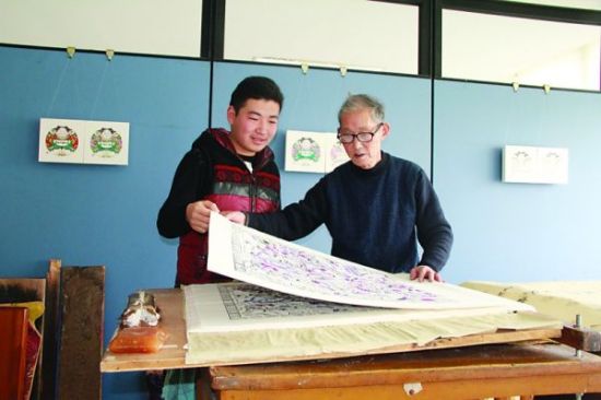 师傅房志达正在教王晟航如何保护印有年画的生宣纸。记者袁艺 摄