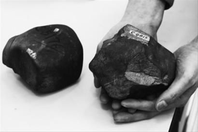 刘金远手拿一块黑色陨石向记者介绍大连陨石情况。 记者 阎华 摄