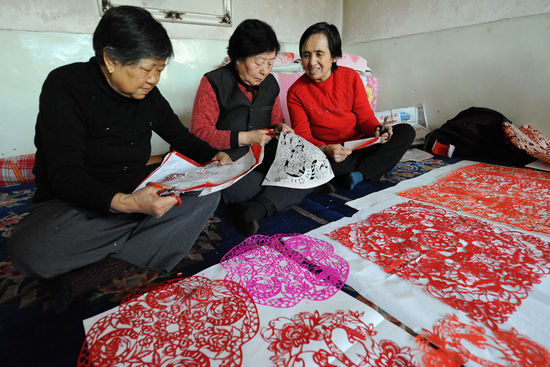 1月28日，陕西神木县剪纸协会会员们在炕头一起创作新春剪纸作品。