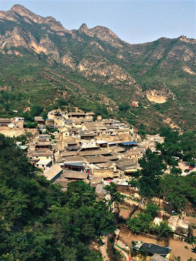 5月22日中午，90多岁的杨文忠坐在大院门槛上，倚着门边的雕花石鼓，低头打盹。门前的道路空无一人。