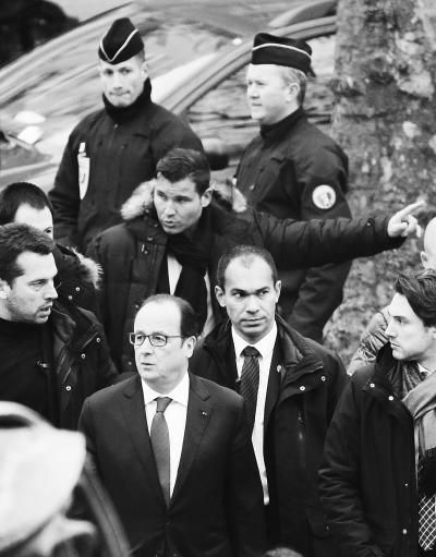 在法国巴黎，法国总统奥朗德(前)来到遭受袭击的《沙尔利周刊》总部。