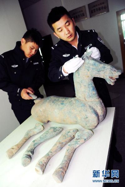 公安民警展示被盗卖的古墓殉葬文物青铜马（2014年10月31日摄）。 