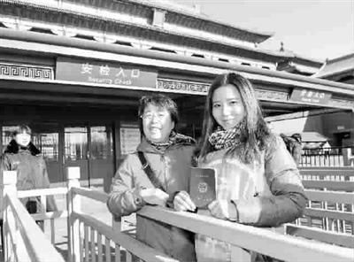 图为昨日，一名教师(右)在故宫博物院入口处展示教师资格证 新华社 发