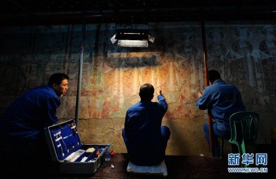 9月3日，三名技术人员在莫高窟98窟内对病害壁画进行修复。新华社记者 陈斌 摄
