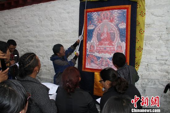 西藏自治区普查办的索朗杰布在林芝羌纳寺现场进行可移动文物普查培训的现场教学。他以一幅唐卡为例，一边量尺寸一边细致讲解唐卡的登记方法。徐秀丽 摄 