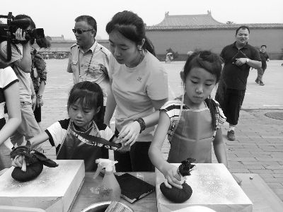 同学们在工作人员的指导下参与“击扫黑白，传拓万千”活动。