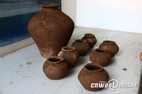 考古人员清理发掘出的陶瓶、陶罐和一枚钱币