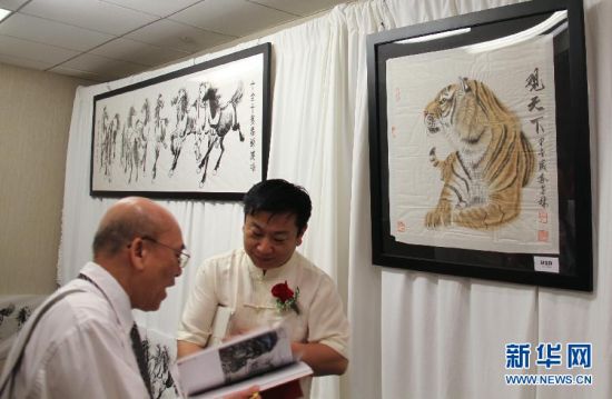 7月10日，中国画家郭金栋（右）在纽约举行的首届中美国际文化艺术品交流展上与参观者交流。
